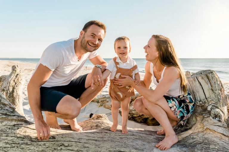 Familie mit kleinem Sohn sitzt auf einem Baumstamm am Strand auf dem Darß (Weststrand Prerow). Es ist eine einzigartige Kulisse für die Familienbilder.