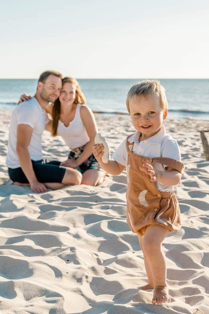 Junger Sohn sammelt Steine am Strand auf dem Darß während dem Familienfotoshooting mit Fotograf aus Dierhagen.
