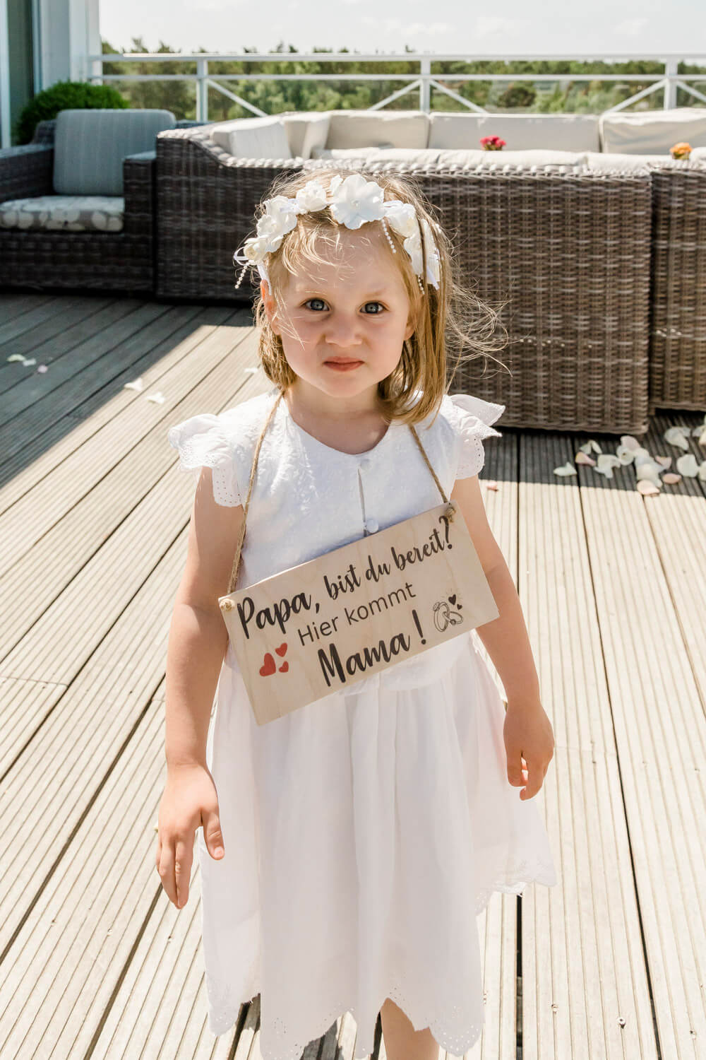 Die Tochter des Hochzeitspaares trägt das Schild "Papa, bist du bereit? Hier kommt Mama" zur Trauung.