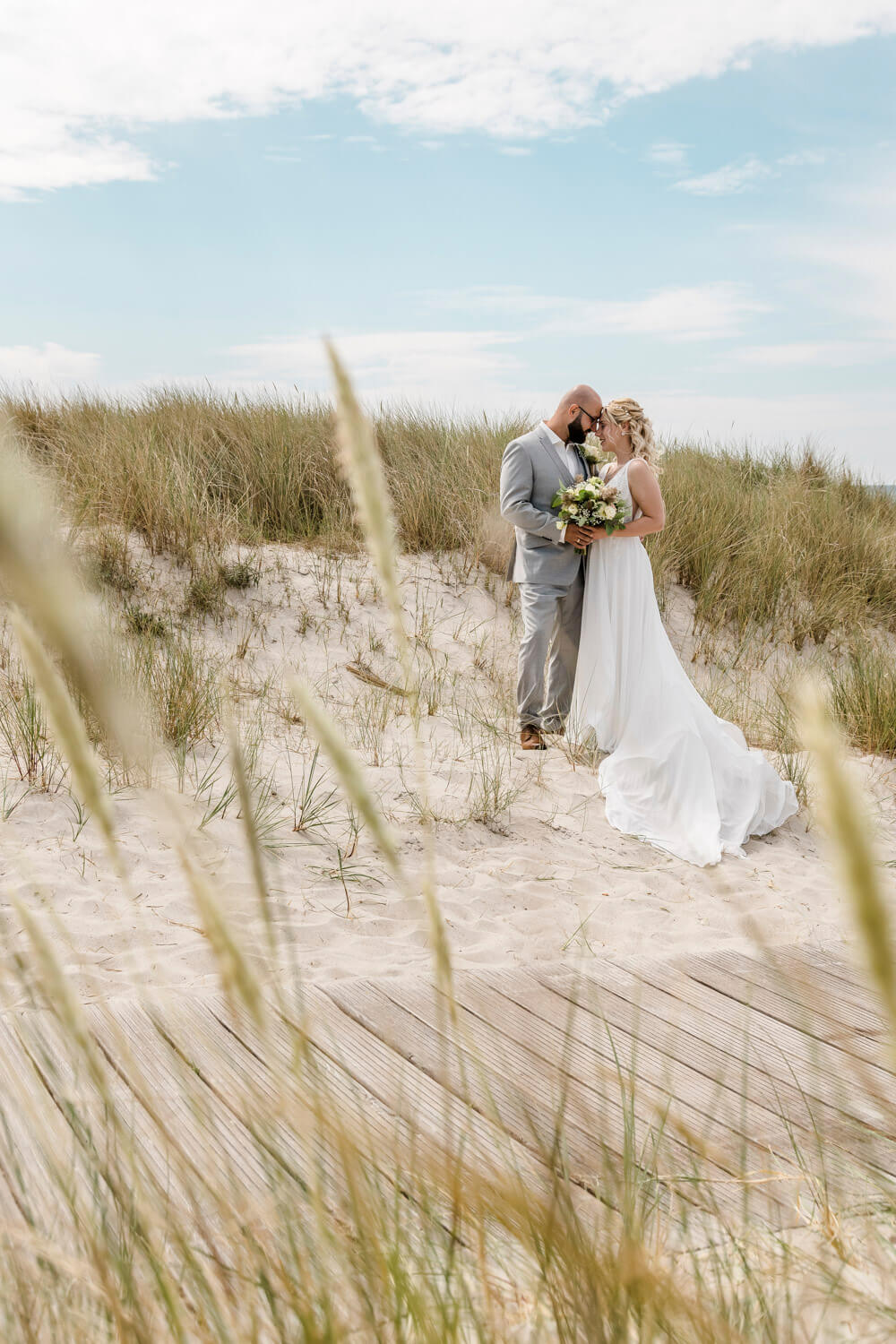 Hochzeit am Strand. Brautpaar steht in den Dünen an der Ostsee. Hochzeitsfotografin.