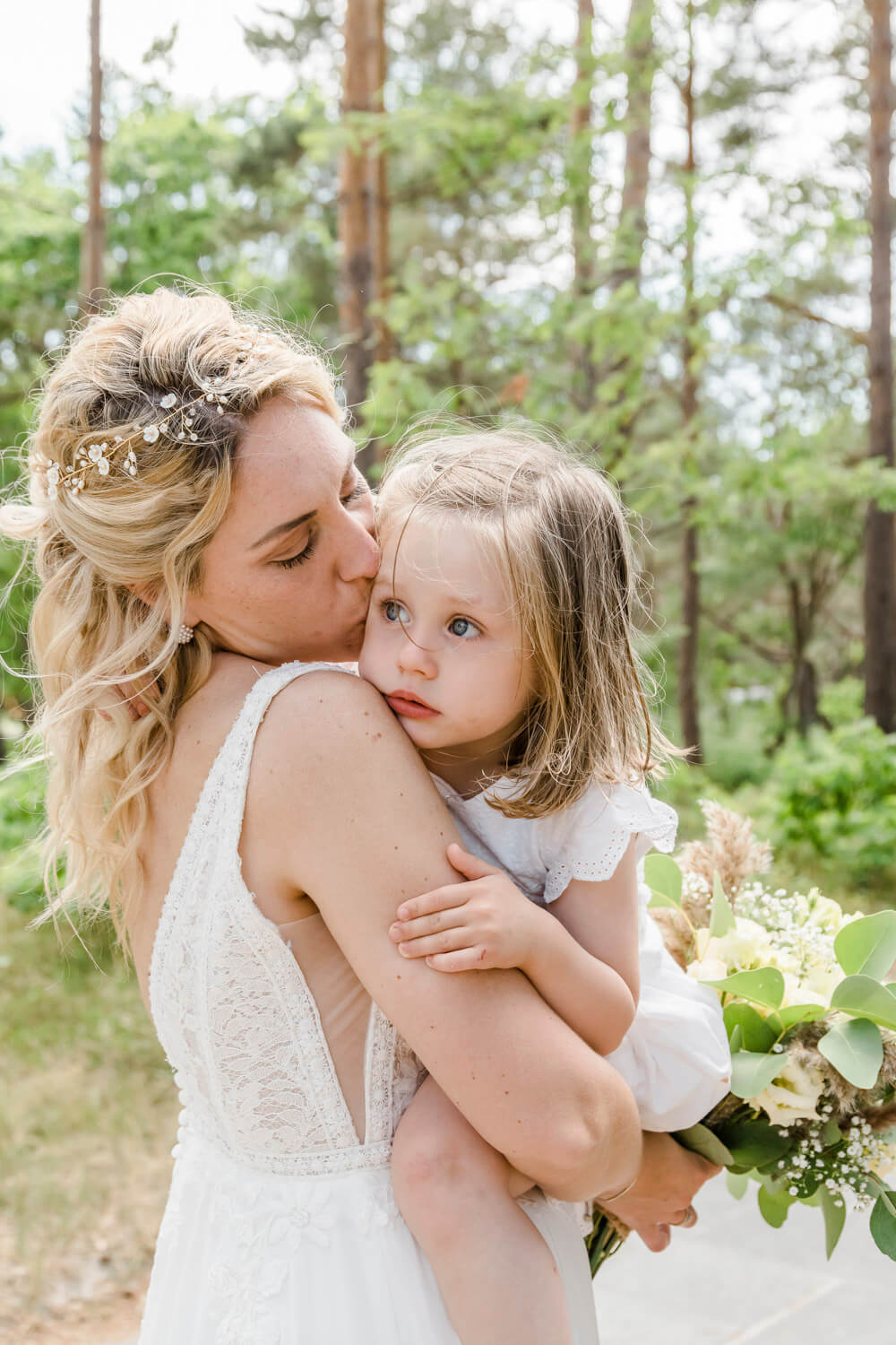 Braut kuschelt ihre Tochter am Hochzeitstag. Fotoshooting im Wald auf dem Darss.