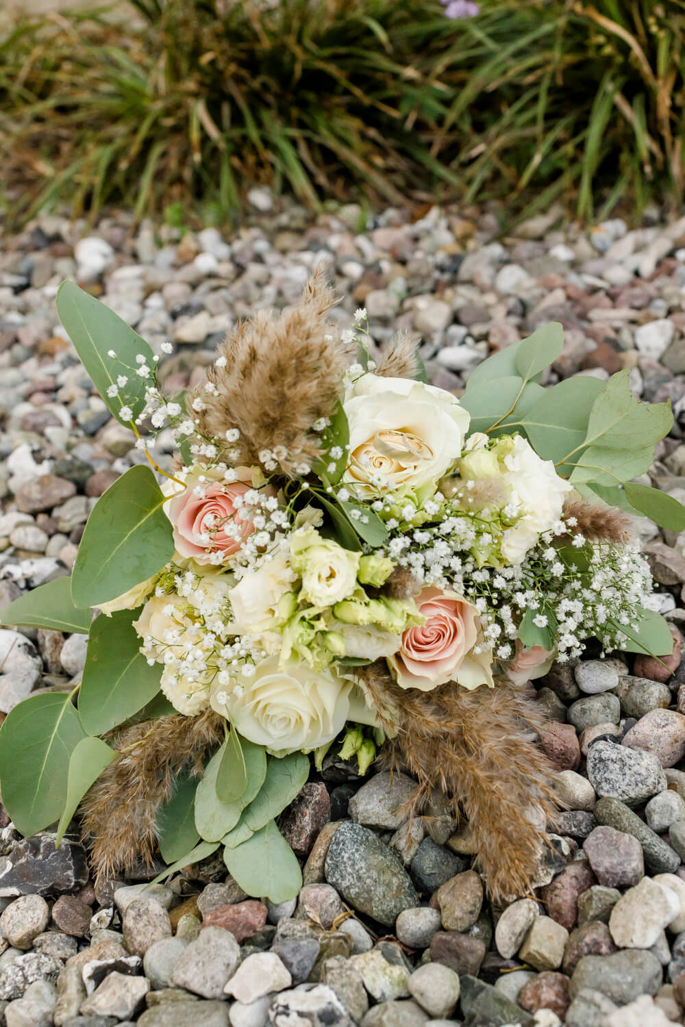 Moderner, lockerer Brautstrauß mit weißen Rosen und Pampasgras. Hochzeitsreportage auf dem Darss.