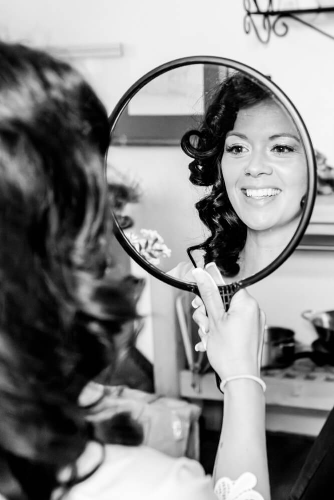 Die Braut bewundert ihr Styling im Spiegel beim Getting Ready.