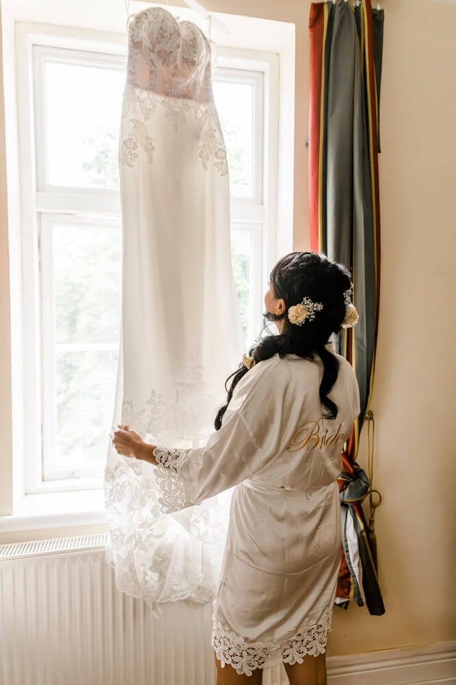 Die Braut bewundert ihr Brautkleid, bevor sie es anzieht.