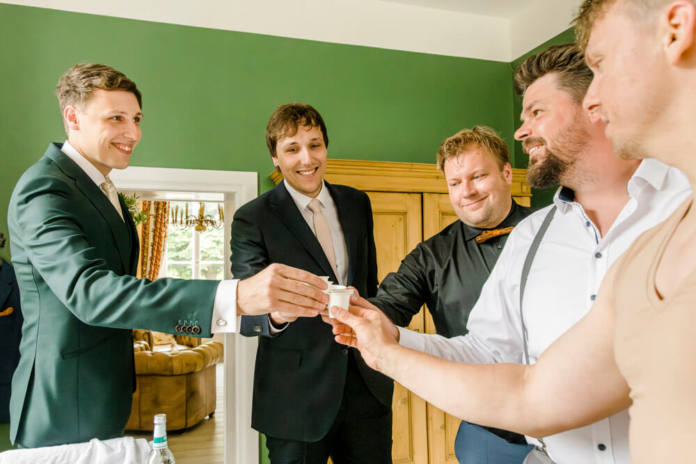 Eine Runde Schnapps mit dem Bräutigam und seinen besten Freunden beim Getting Ready. Hochzeitsreportage Gut Klein Nienhagen.