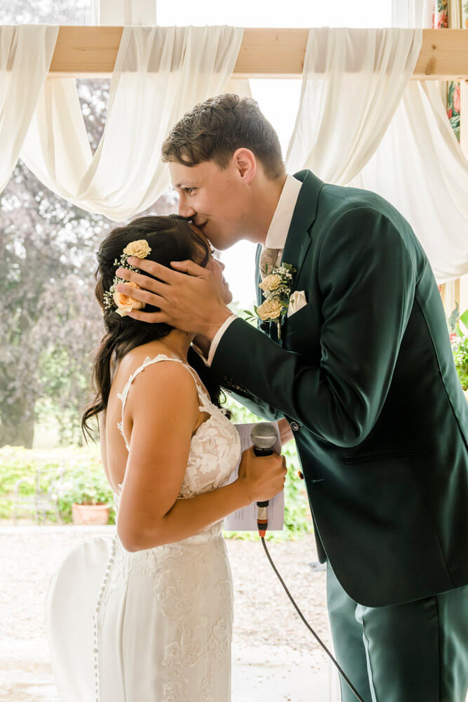 Der Bräutigam gibt seiner Braut einen Kuss auf die Stirn
