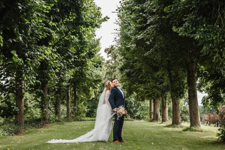 Hochzeitsfotograf im Schloss Vietgest. Das Brautpaar steht in einer Baumallee