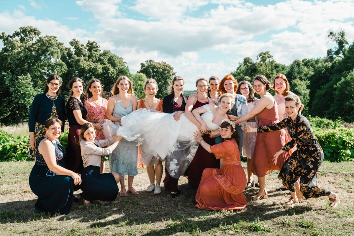 Die Freundinnen heben ihre Braut hoch. Lustiges Gruppenfoto zur Hochzeit.