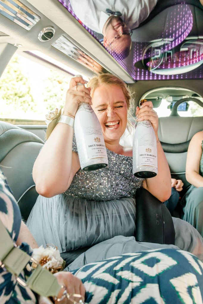 Fröhliche Frau mit Champagner in Limousine feiern