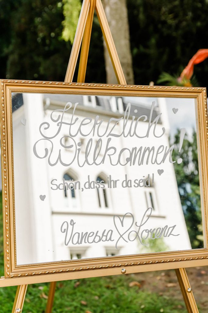 Hochzeitsschild mit Begrüßung vor historischer Kirche