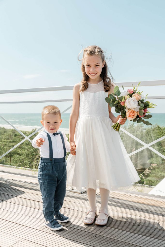 Kinderlächeln am Strand mit Blumenstrauß