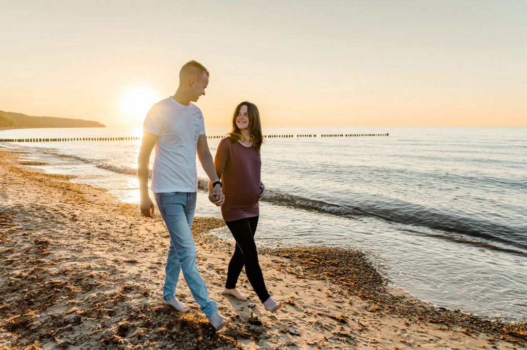 Paar spaziert am Strand bei Sonnenuntergang entlang