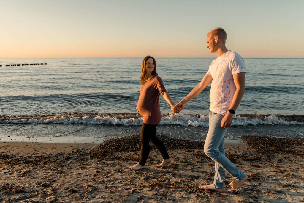 Paar spaziert am Strand bei Sonnenuntergang.