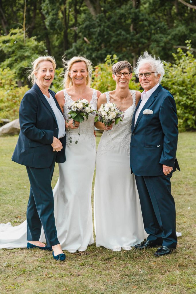 Glückliches Hochzeitspaar mit Familienmitgliedern im Freien