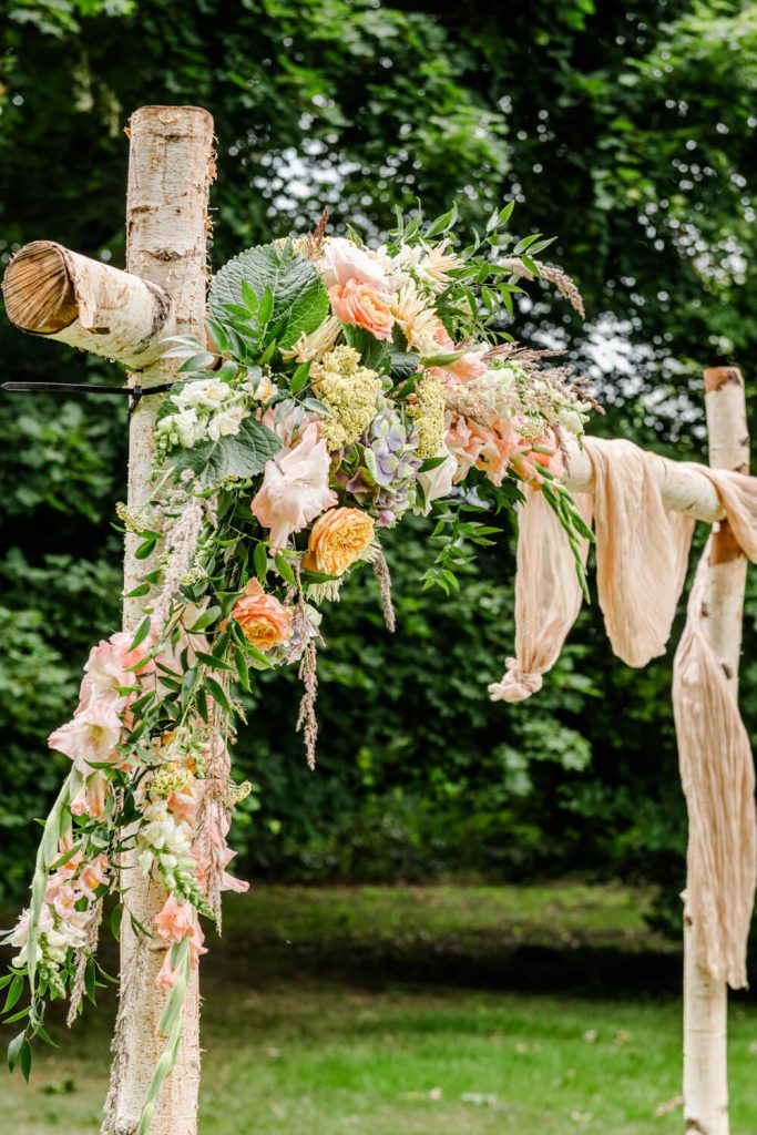 Blumengesteck auf rustikaler Hochzeitsdekoration im Freien