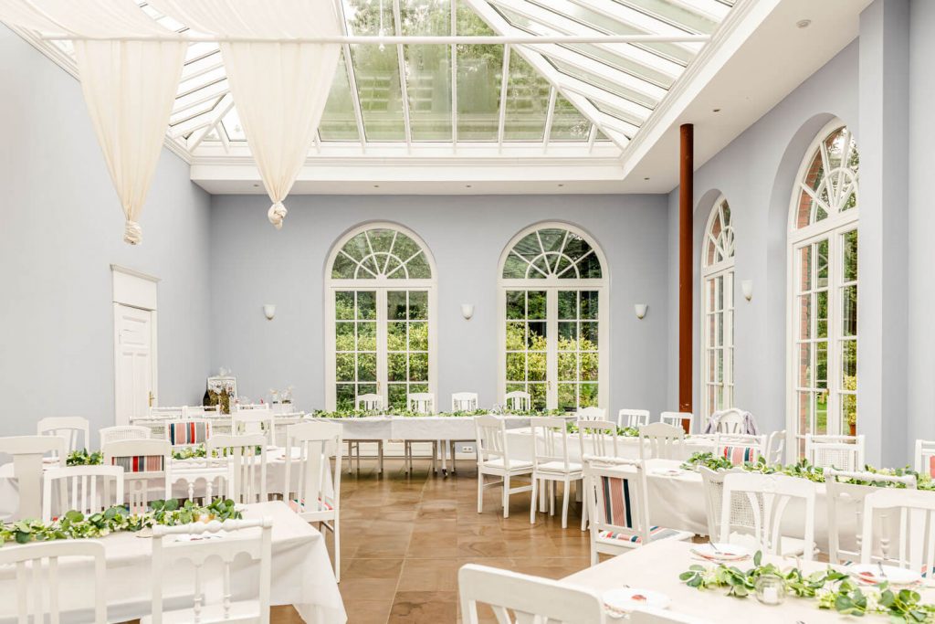 Gut Groß Siemen. Heller Veranstaltungsraum mit weißer Einrichtung und Pflanzen