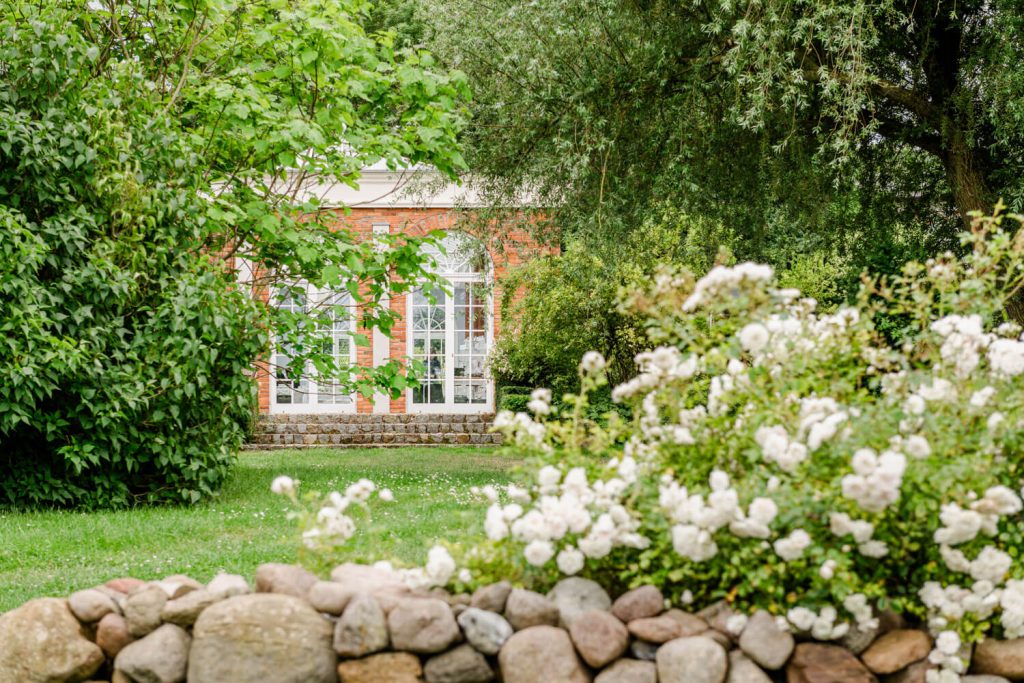 Gut Groß Siemen. Backsteinbau mit Garten und blühenden Sträuchern