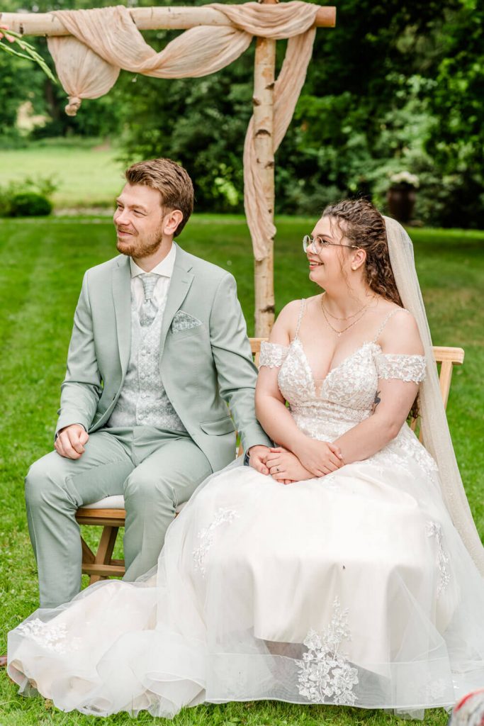 Brautpaar sitzt bei einer Hochzeit im Freien. Gut Groß Siemen.