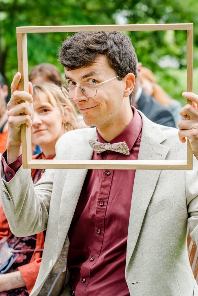 Mann mit Brille hält leeren Rahmen hoch