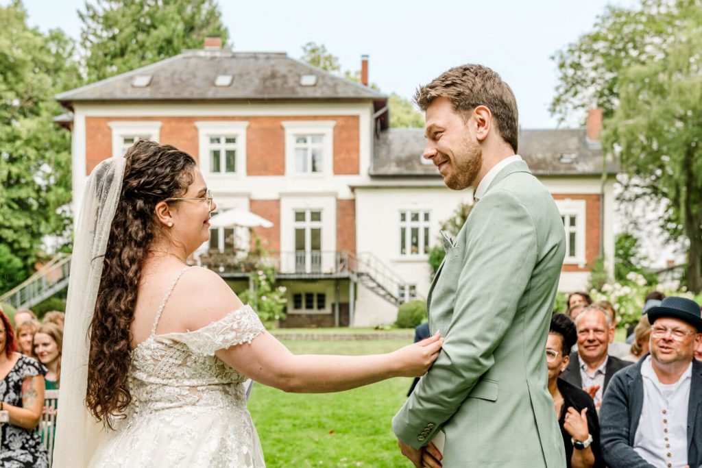 Brautpaar lächelt bei der Hochzeitszeremonie im Freien. Gut Groß Siemen.