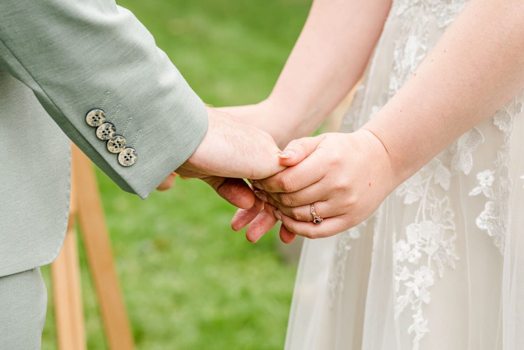Paar hält Hände bei einer Hochzeit im Freien