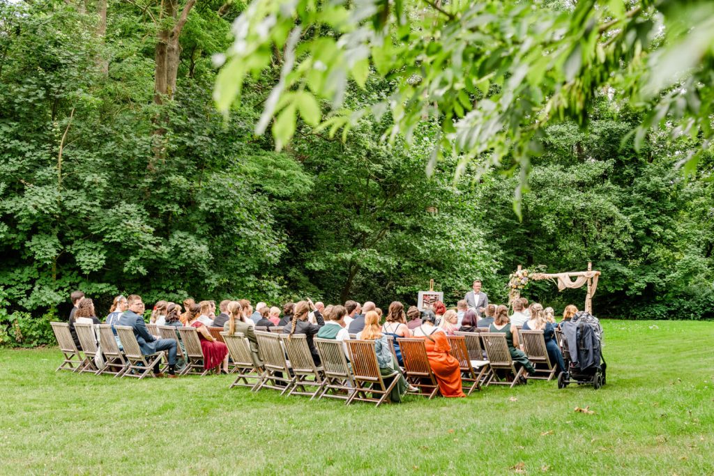 Gäste bei einer Hochzeit im Freien sitzen zusammen.