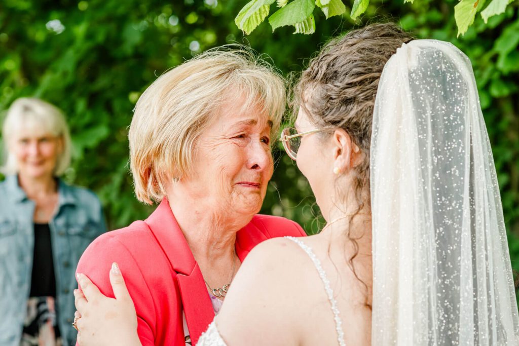 Ältere Frau umarmt Braut im Freien Hochzeit