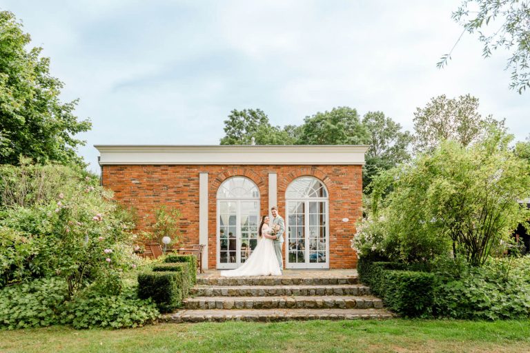 Gut Groß Siemen. Brautpaar vor historischem Backsteingebäude im Garten