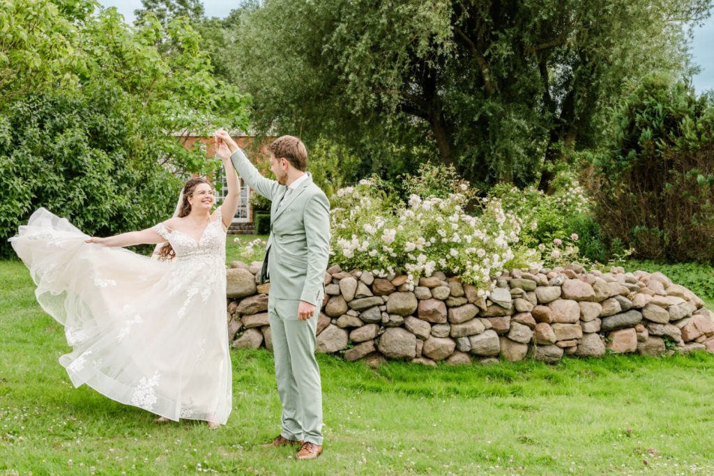 Gut Groß Siemen. Brautpaar tanzt glücklich im grünen Garten.