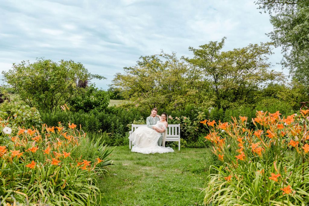 Gut Groß Siemen bei Rostock. Brautpaar auf weißer Bank im Garten