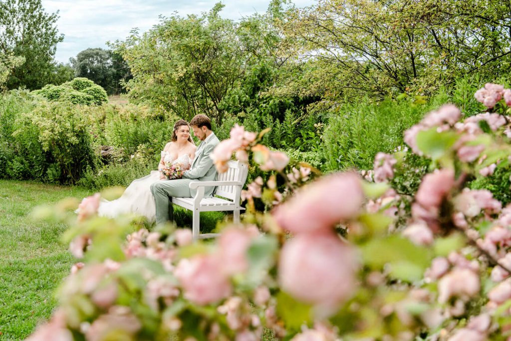 Brautpaar sitzt auf Bank im blühenden Garten