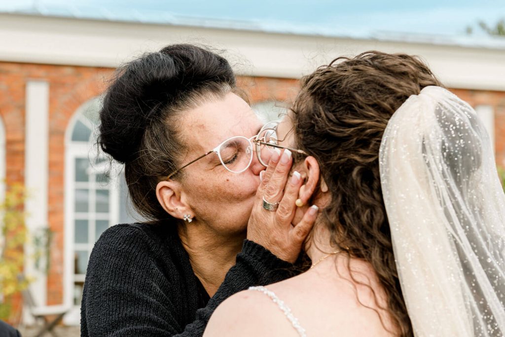 Ältere Frau umarmt Braut an ihrem Hochzeitstag