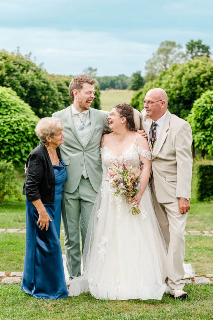 Hochzeitspaar mit Familie im Garten lachend