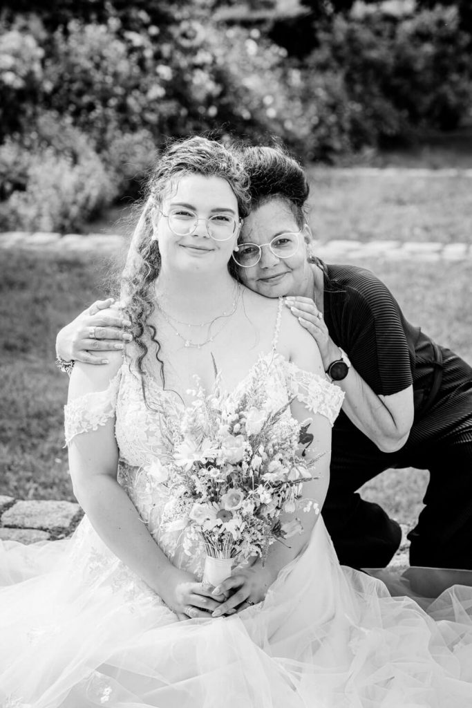 Braut mit Blumenstrauß und Begleiter im Garten