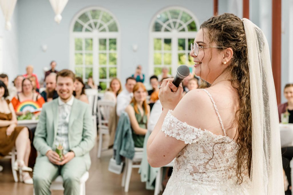 Braut hält Rede auf Hochzeitsfeier vor Gästen