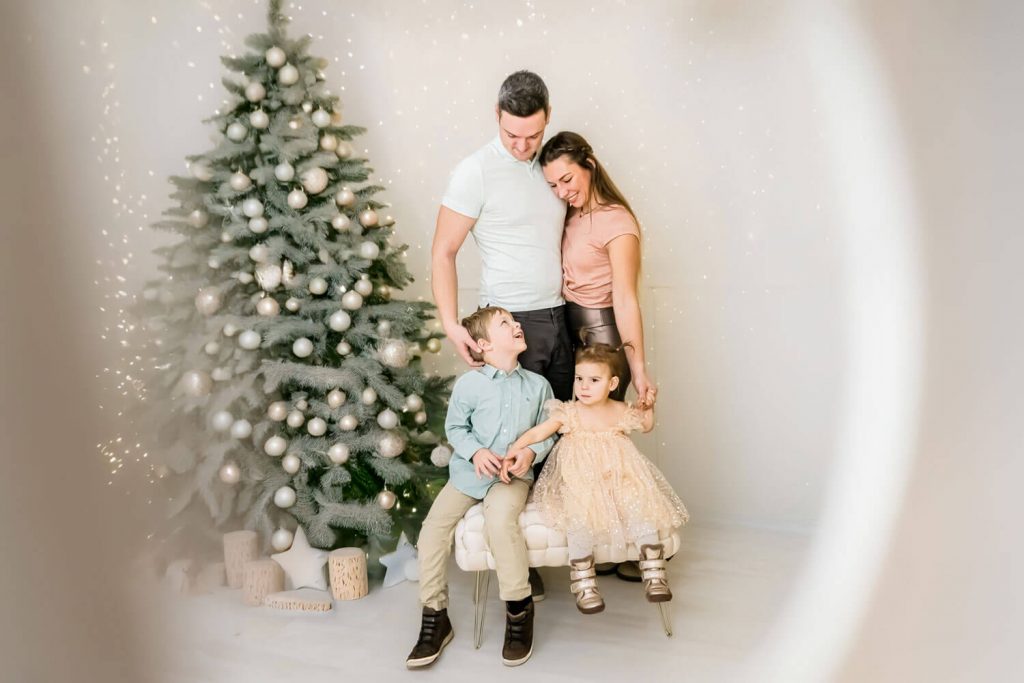 Familie posiert glücklich neben dem Weihnachtsbaum