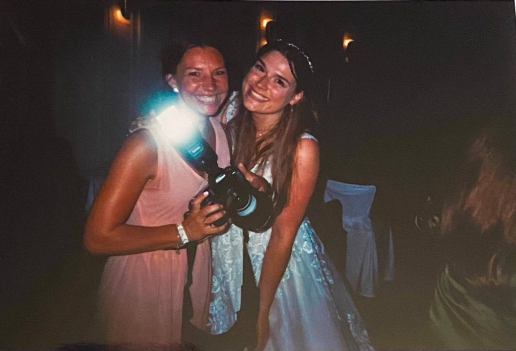 Zwei lächelnde Frauen auf Hochzeitsfeier mit Kamera