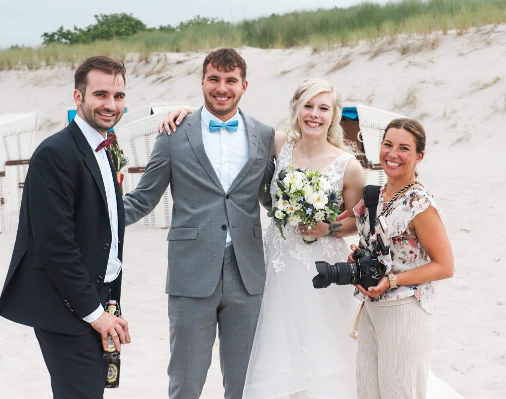 Vier Personen lächeln bei einer Strandhochzeit