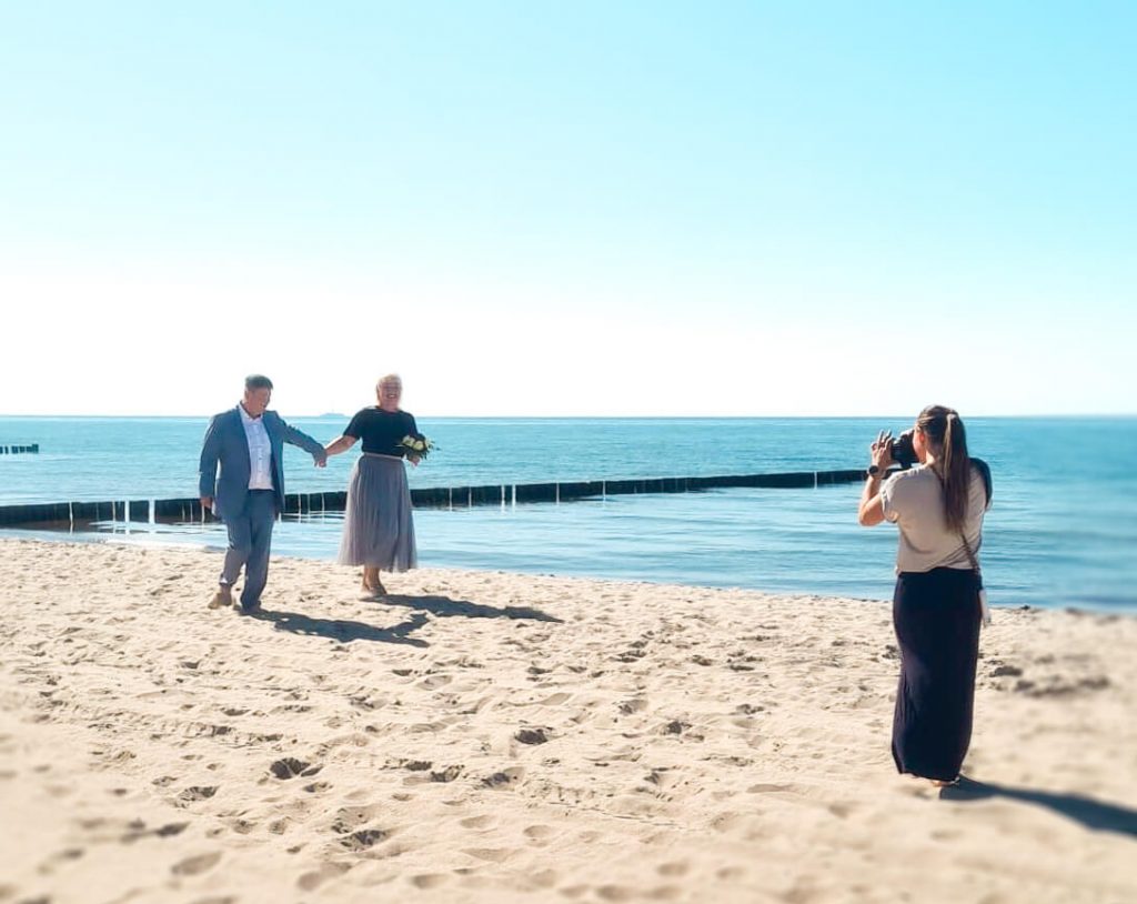 Paar beim Fotoshooting am sonnigen Strand.