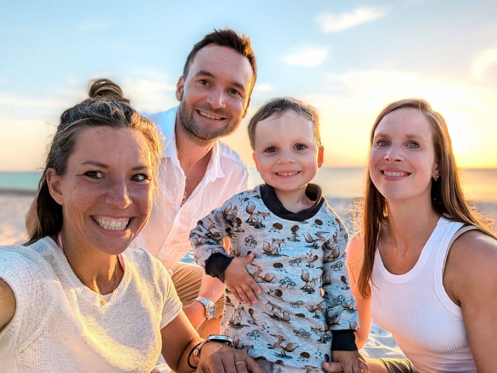 Glückliche Familie lächelt am Strand bei Sonnenuntergang