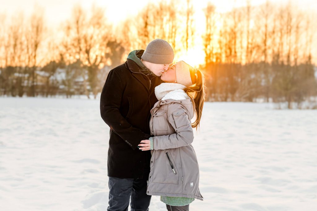 Paar küsst sich vor Sonnenuntergang im Schnee