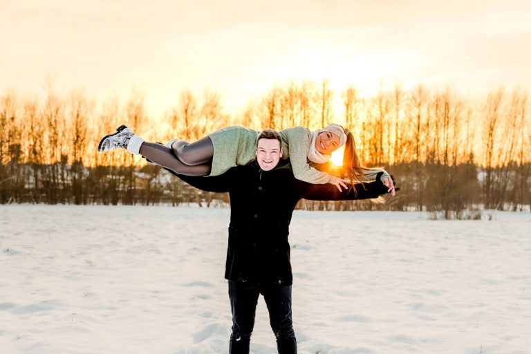 Paar lacht beim Winterspaziergang im Schnee.