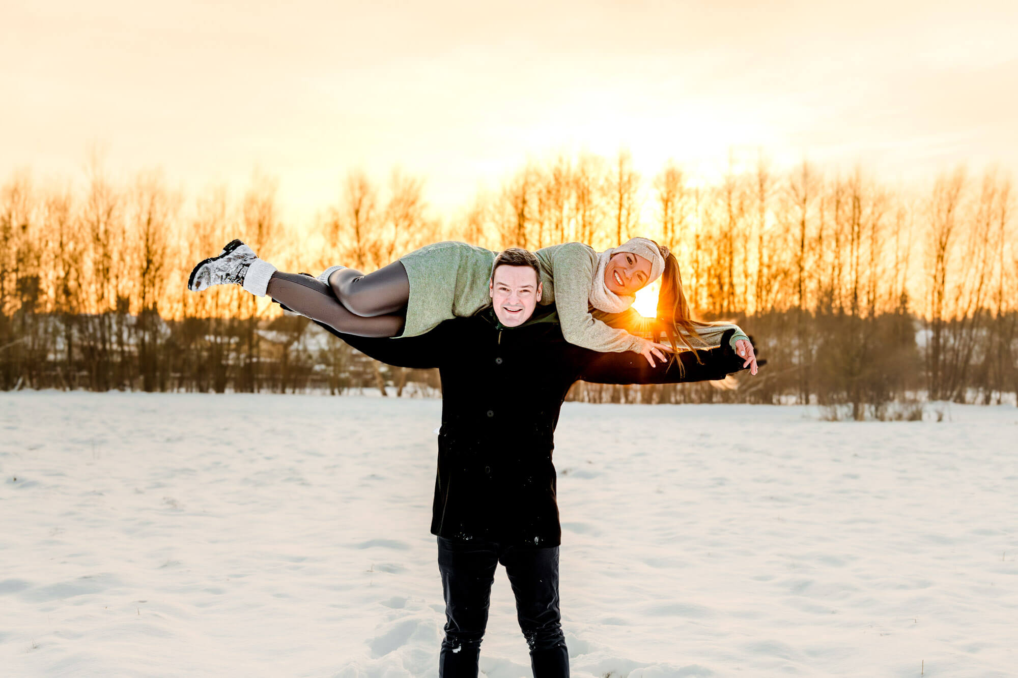 Paar lacht beim Winterspaziergang im Schnee.