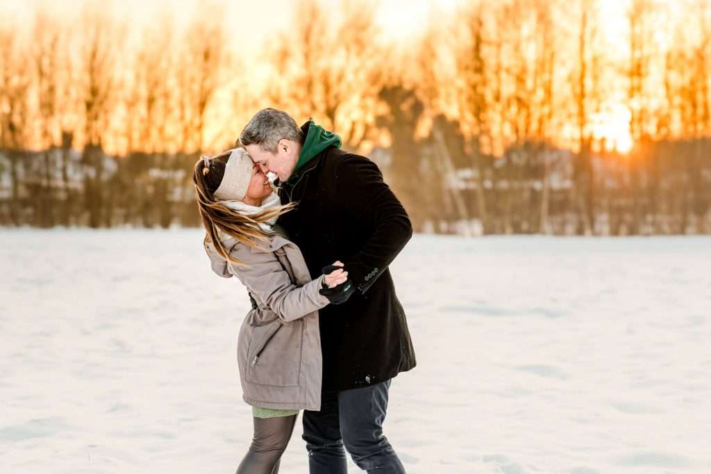 Paar tanzt im Schnee bei Sonnenuntergang Winter