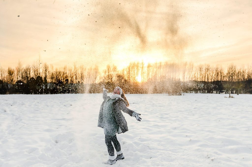 Frau erfreut sich am Schnee bei Sonnenuntergang