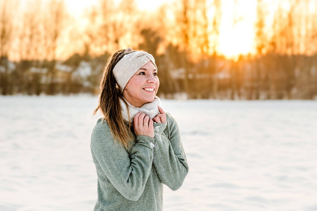 Frau im Schnee lächelt in der Wintersonne