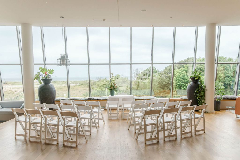 Heller Veranstaltungsraum mit Stühlen und großen Fenstern