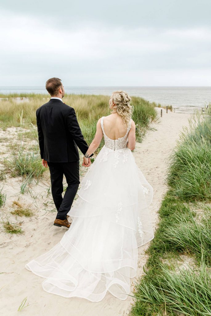 Brautpaar spaziert am Strand entlang Richtung Meer