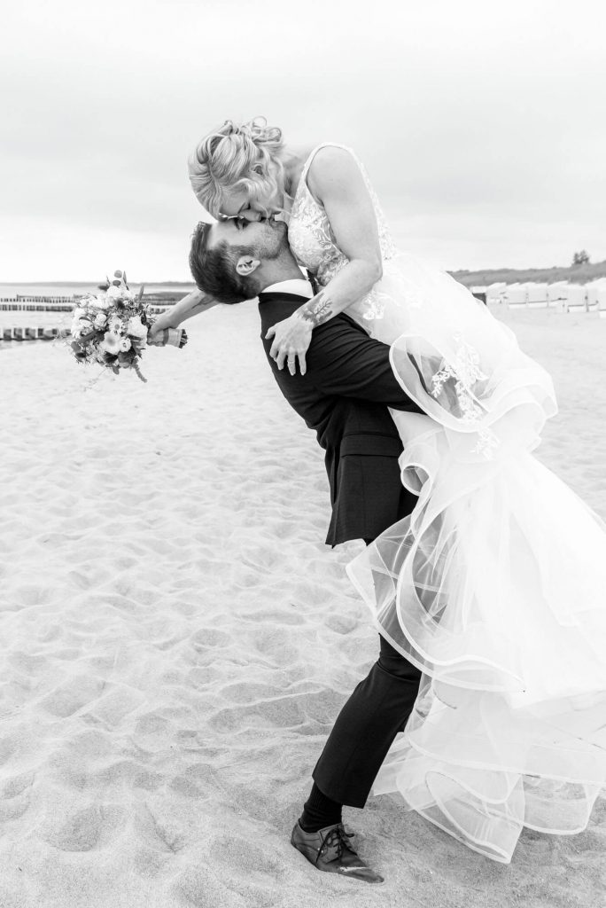 Brautpaar am Strand beim Hochzeitsshooting küssend.
