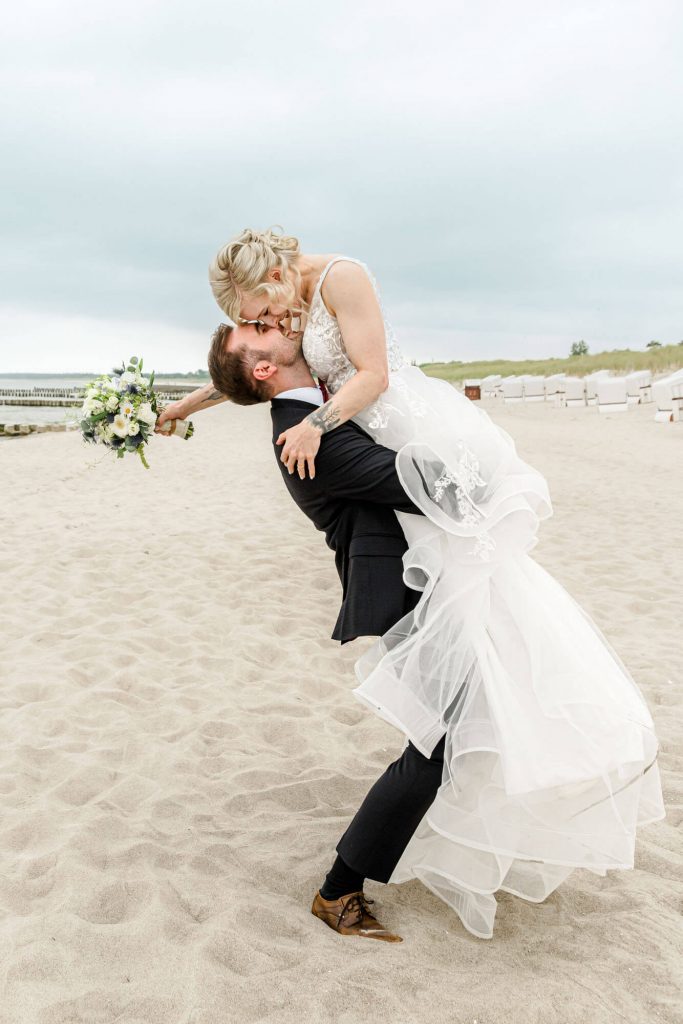 Ein Hochzeitspaar am Strand umarmt romantisch.